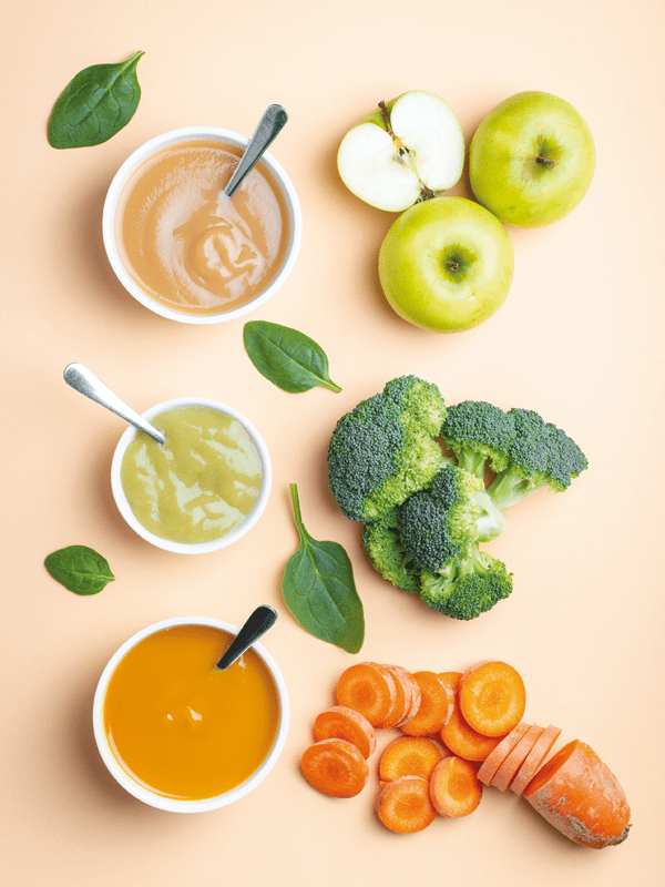 Brei oder Baby-led weaning Ernährung bei Beikoststart? Karotten und Karottenbrei in einer Schüssel, Brokkoli und Brokkolibrei in einer Schüssel, Apfel und Apfelbrei in einer Schüssel.